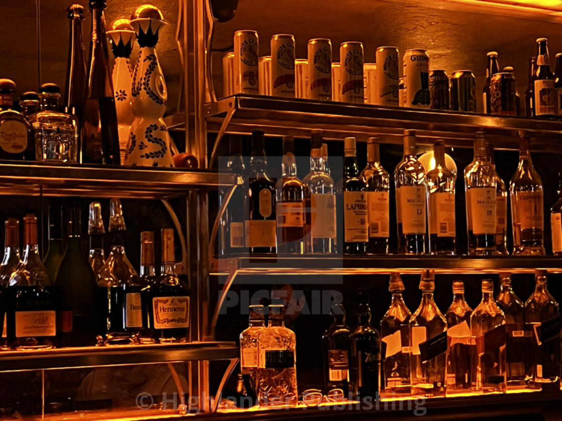 "Liquor bottles at bar bathed in red light" stock image