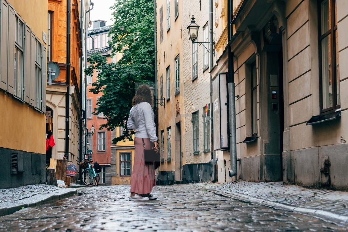 "Beautiful young woman is looking back in a picturesque and narrow cobblestoned street" stock image