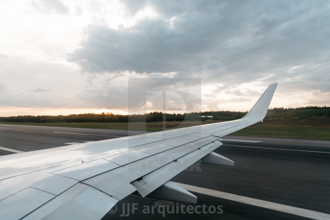 "Wing of a flying airplane landing on runway" stock image