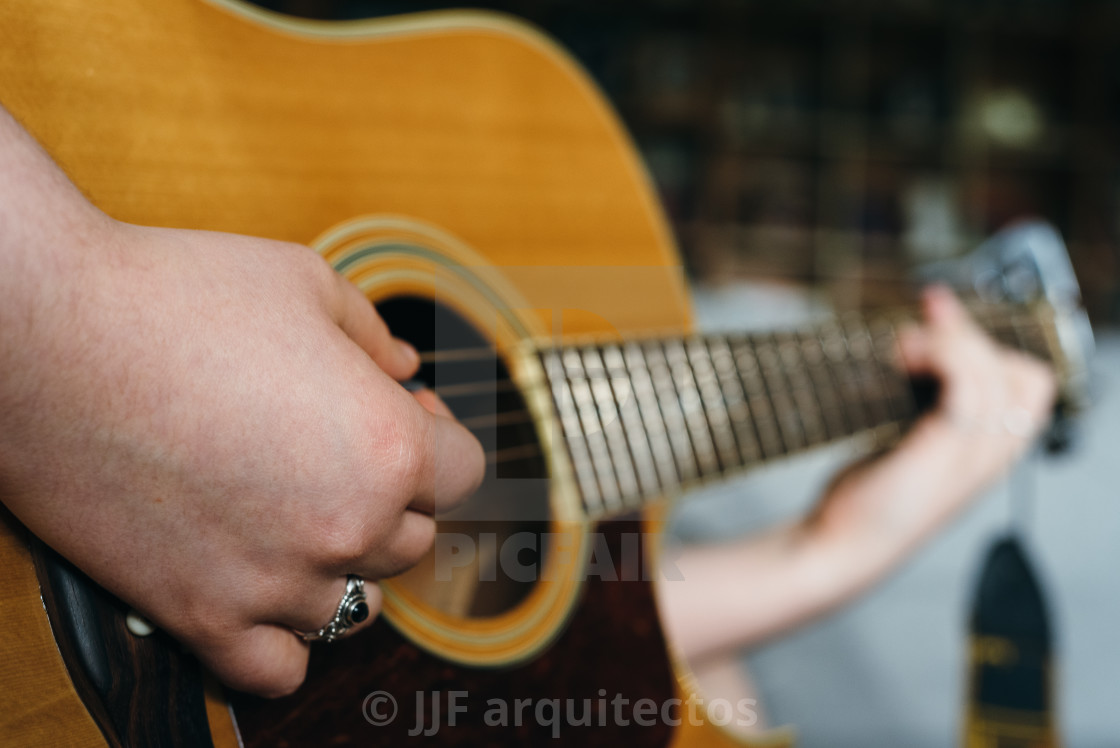 "Young woman playing acoustic guitar at home" stock image