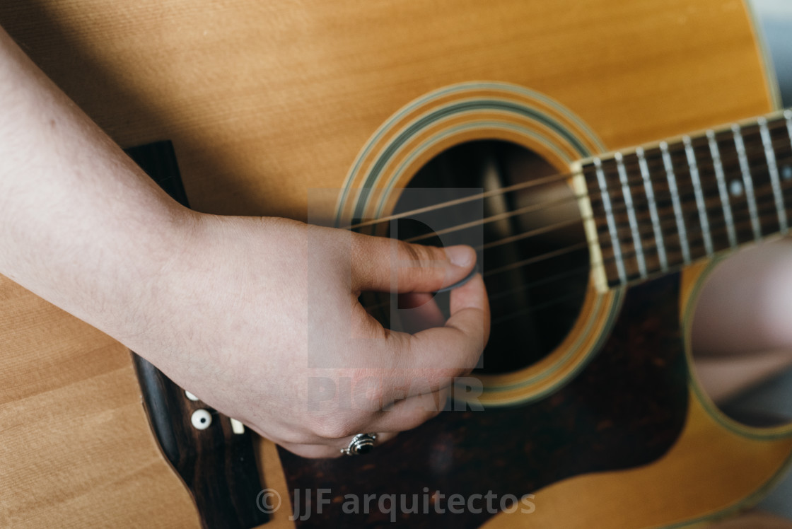 "Young woman playing acoustic guitar at home" stock image