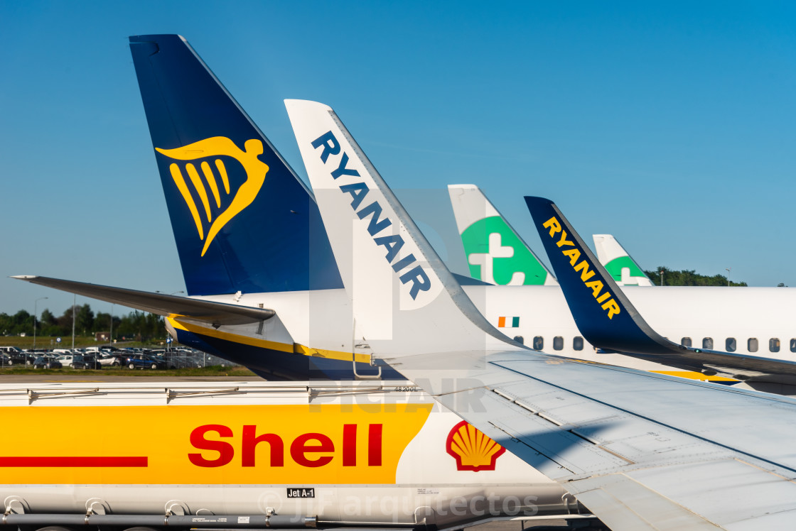 "Tail rudders and wings of airliners lined up on an airport runway" stock image