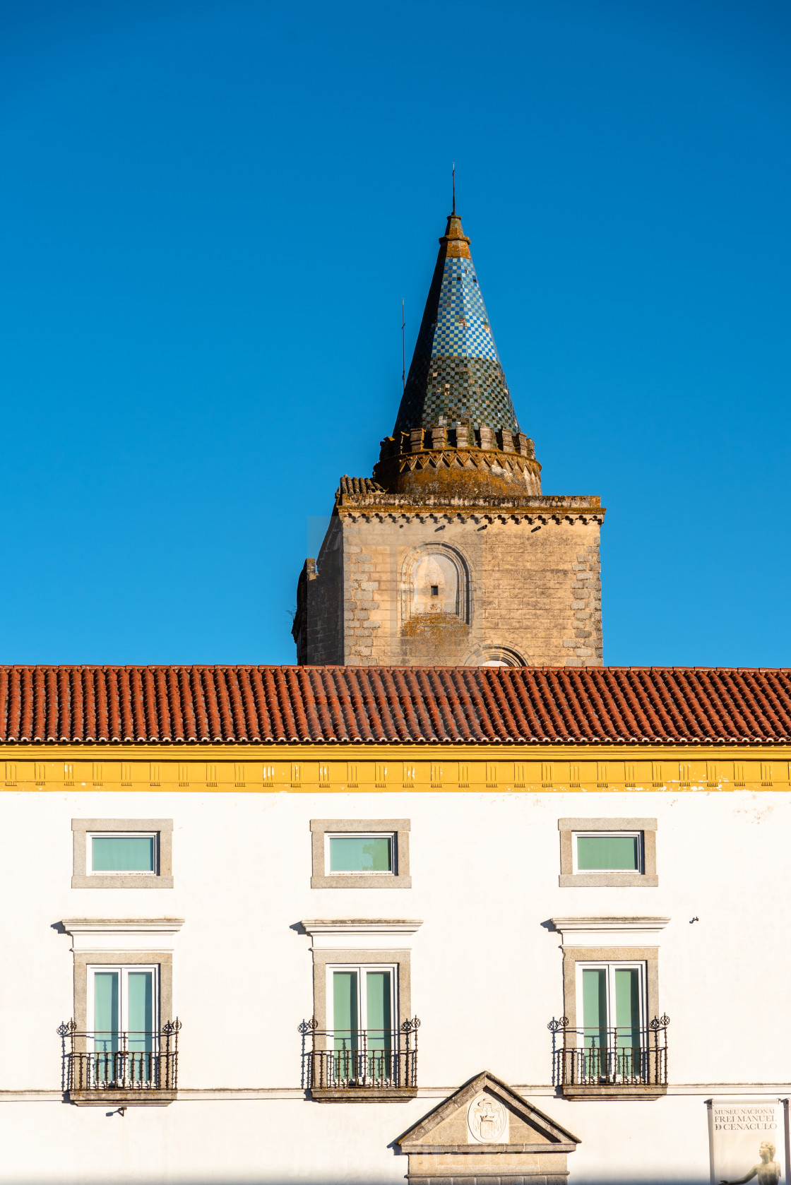 "The tower of the Cathedral of Evora and buildings painted in white and yellow with ceramic tiled roofs" stock image