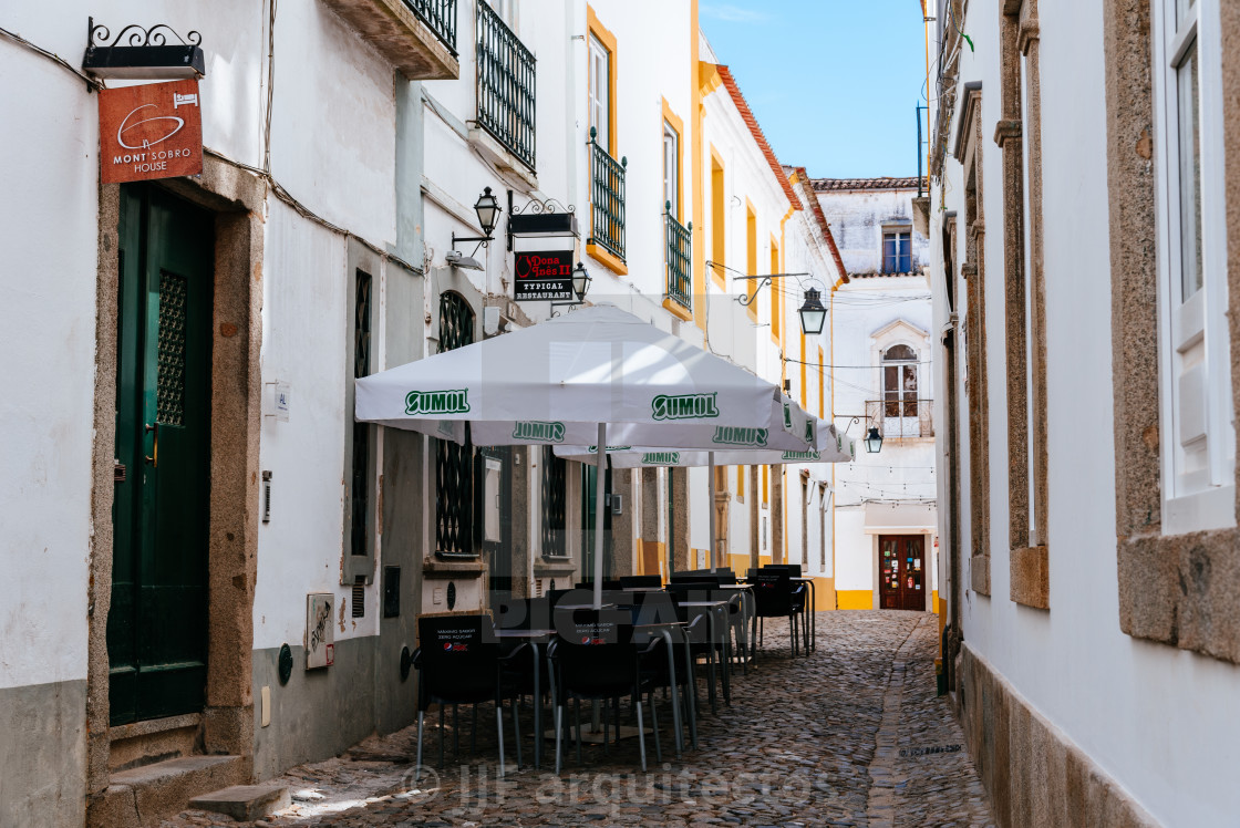 "Narrow street in the old town of Evora with restaurant terrace" stock image