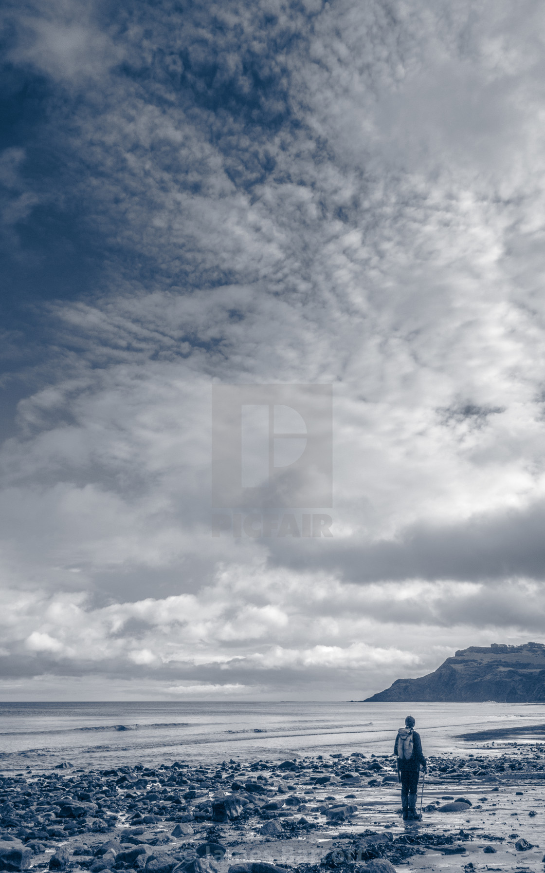 "Lone figure on rocky shore" stock image