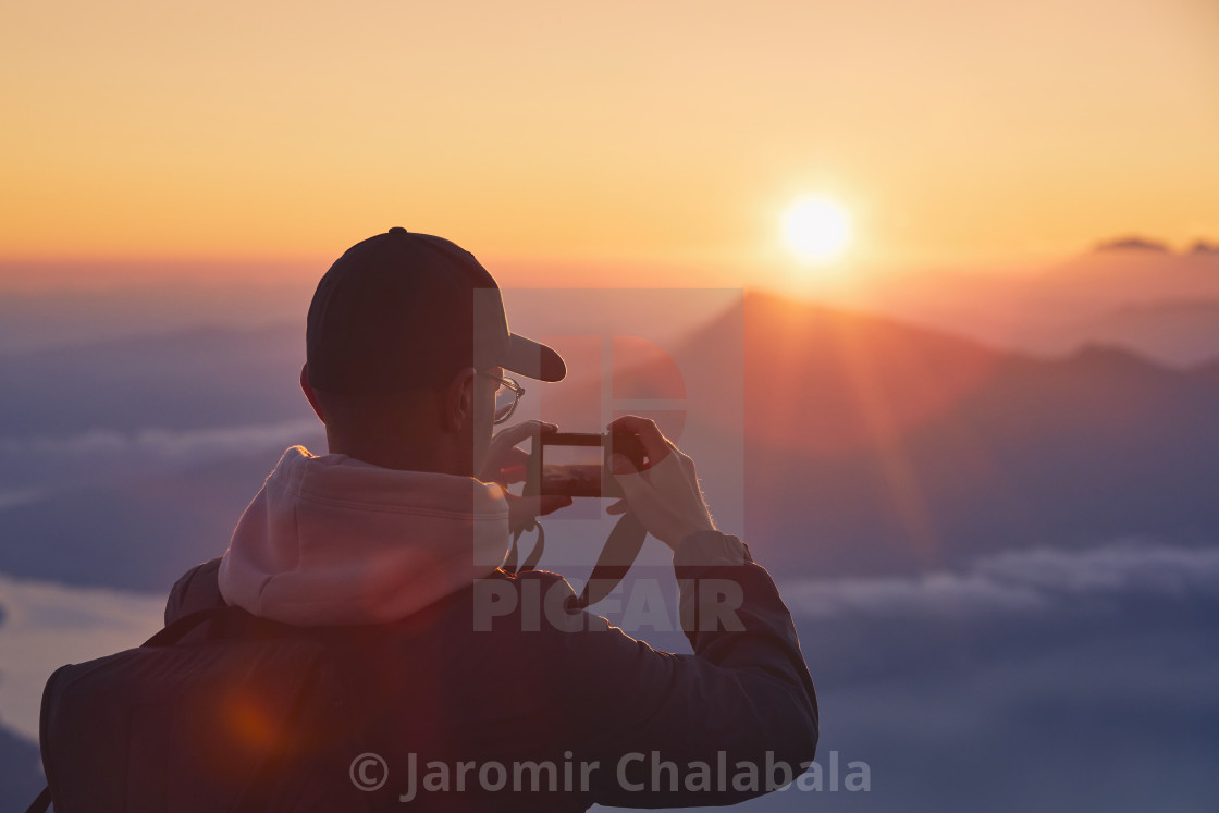 "Man on top of mountain photographing sunrise" stock image