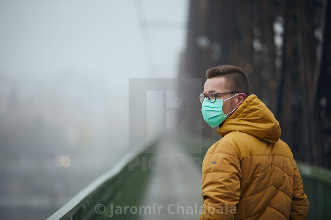 "Lonely man wearing face mask against city in fog" stock image