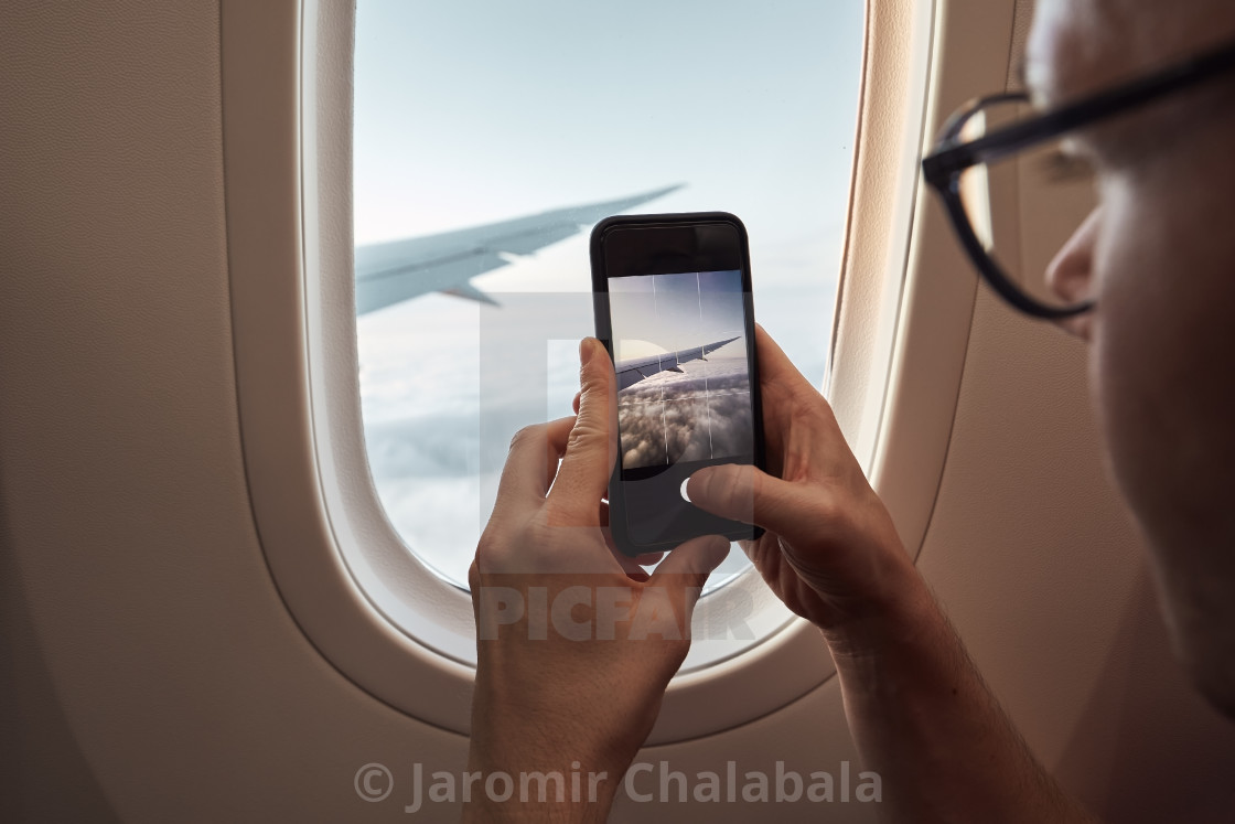 "Passenger photographing through airplane window" stock image