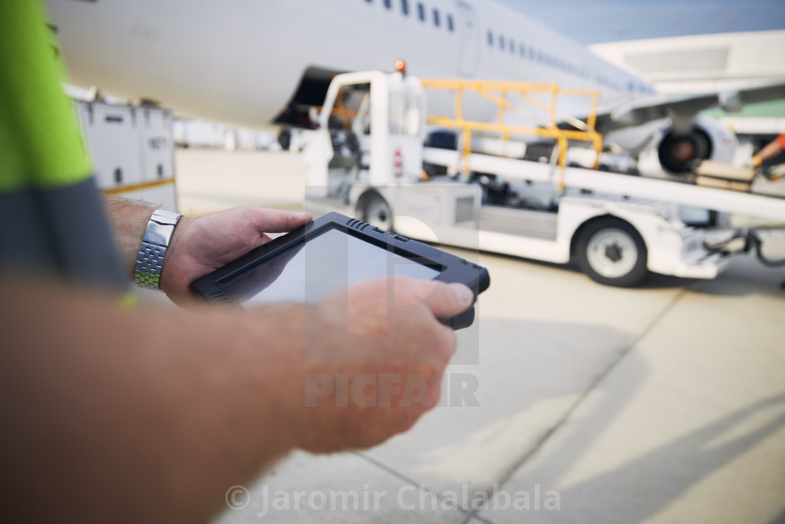 "Member of ground staff using tablet against plane at airport" stock image