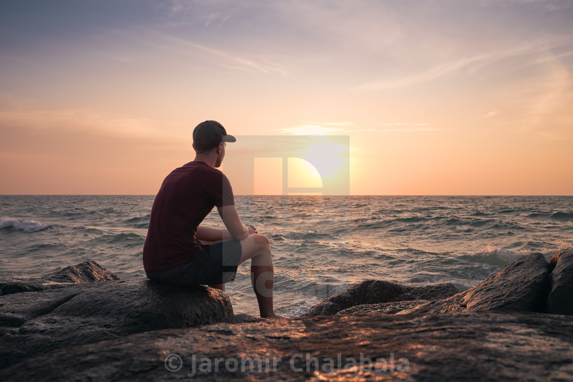 "Man watching beautiful sunset over ocean" stock image