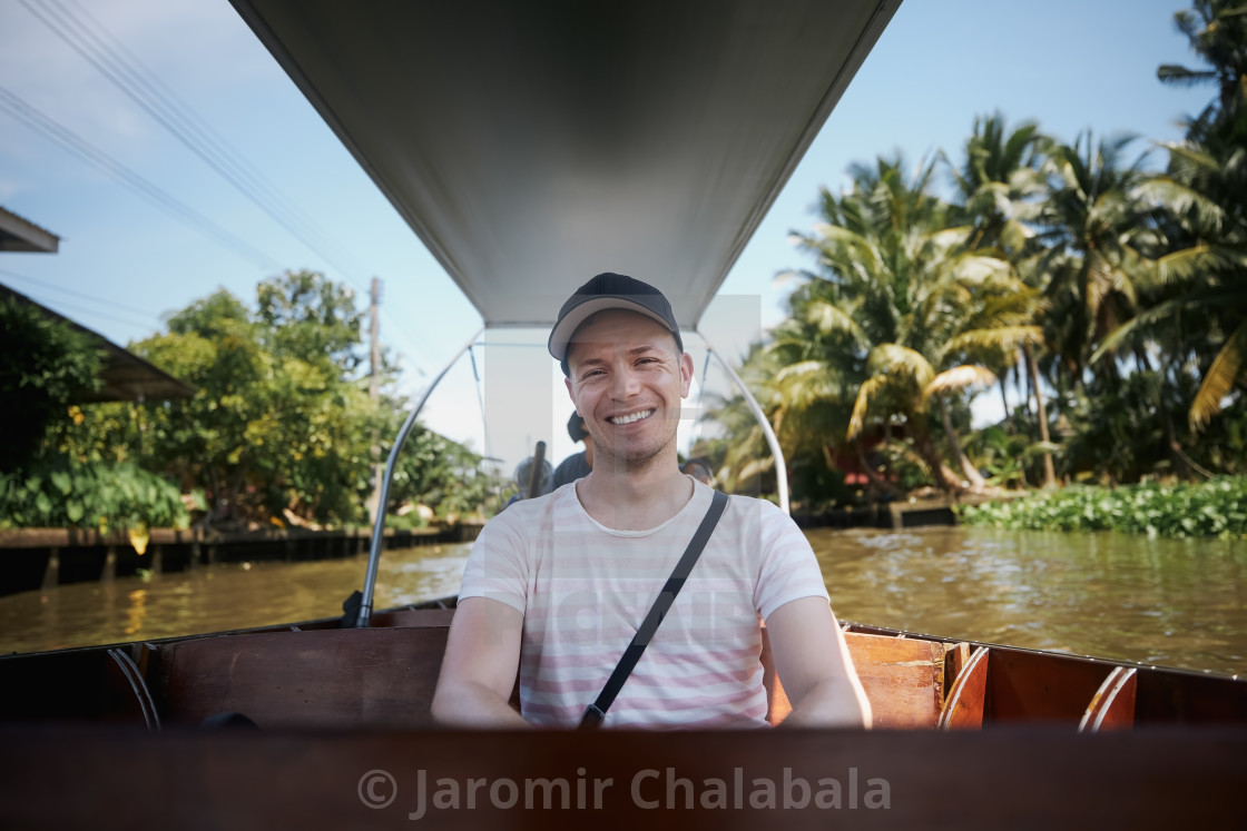 "Happy man enjoys boat trip to floating market in Thailand" stock image