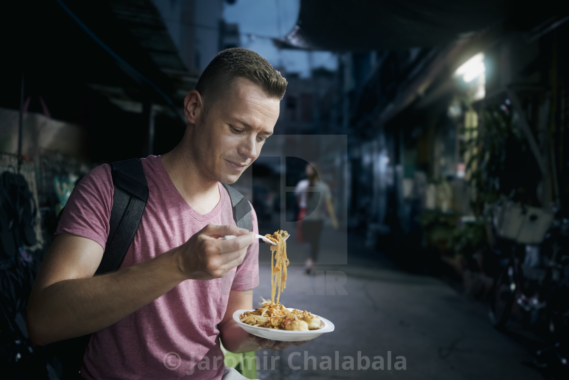 "Tourist eating pad thai at night street market" stock image