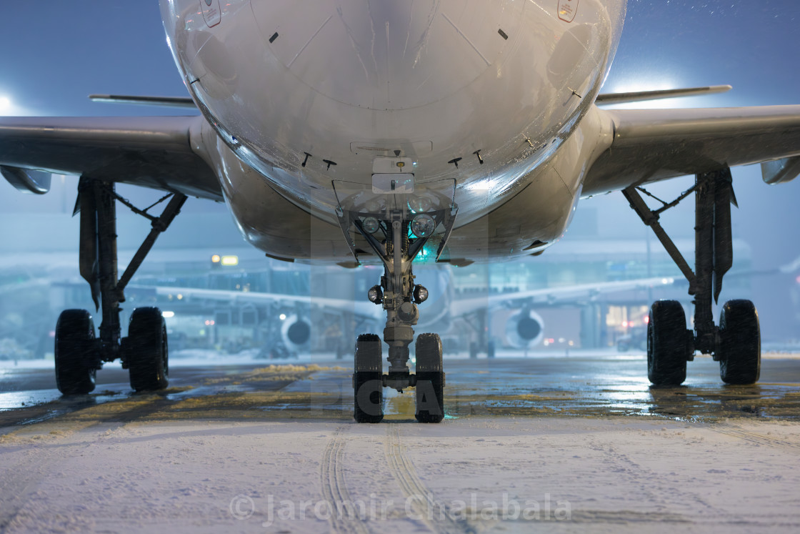 "Airplane on winter frosty night at airport during snowfall" stock image