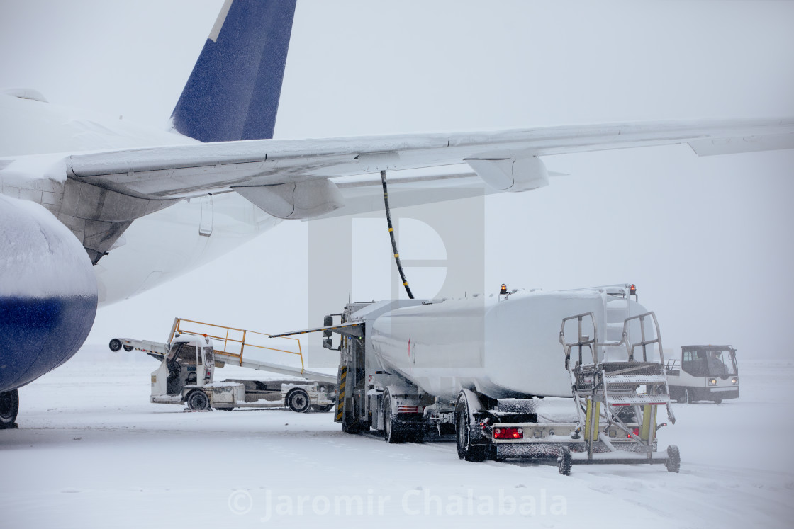 "Refueling of airplane at airport during snowfall" stock image