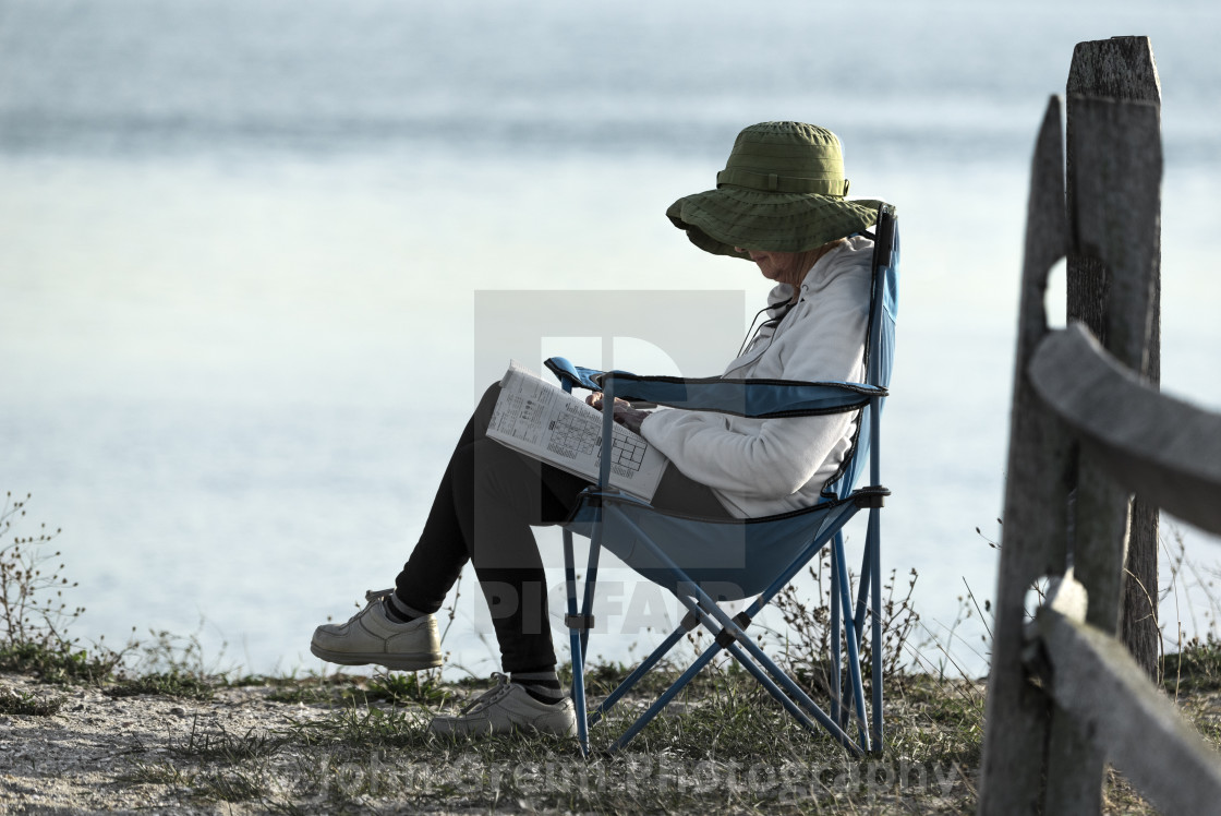 "Senior woman works on a crossword puzzle" stock image