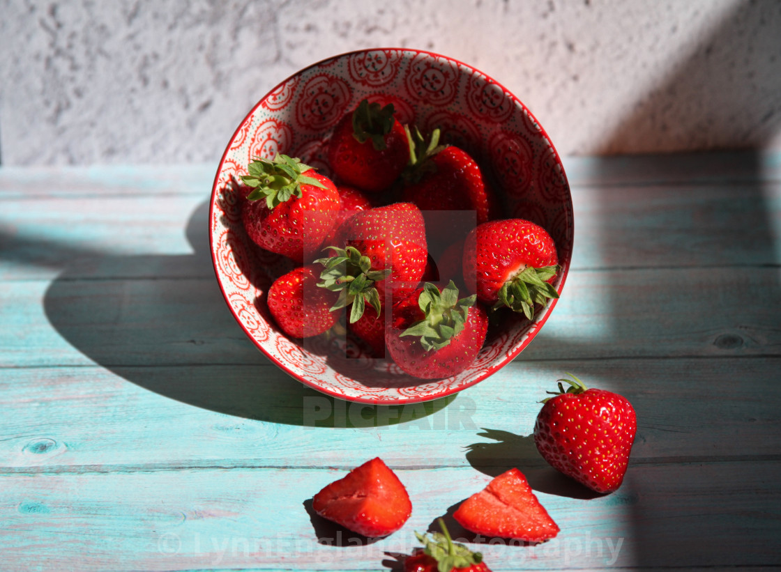 "Tipped bowl of strawberries" stock image