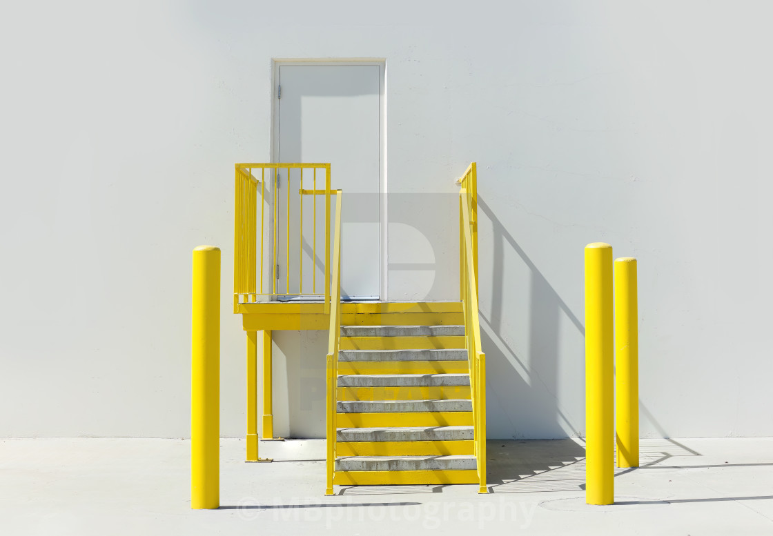 "Empty wall of a warehouse with yellow stairs and poles" stock image