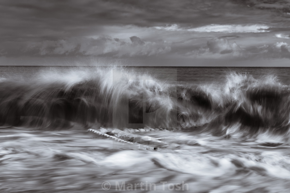 "Wave breaking over old sea defences mono." stock image