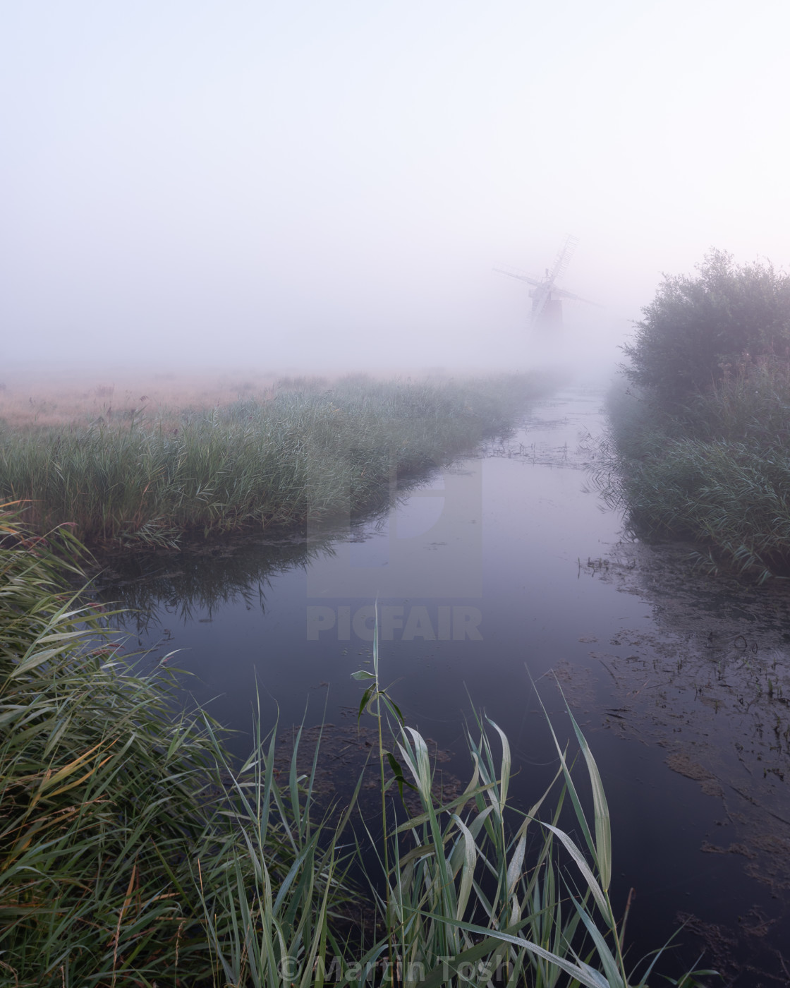 "Norfolk windpump in the mist i reeds and waterway." stock image