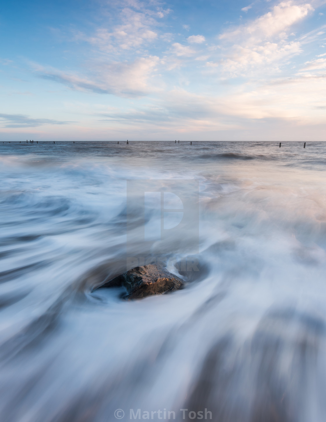 "soft wave motion around Happisburgh beach rock" stock image