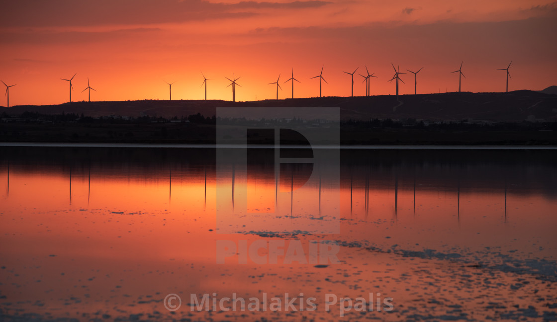 "Sunset at the lake and wind turbines for alternative energy at the slope of the hill." stock image