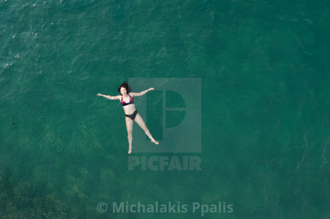 "Woman with swimsuit floating and swimming in blue sea. Overhead shot. Aerial drone photograph" stock image