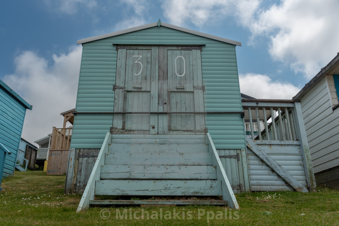 "Colorful holiday beach hut holiday homes against blue cloudy sky" stock image