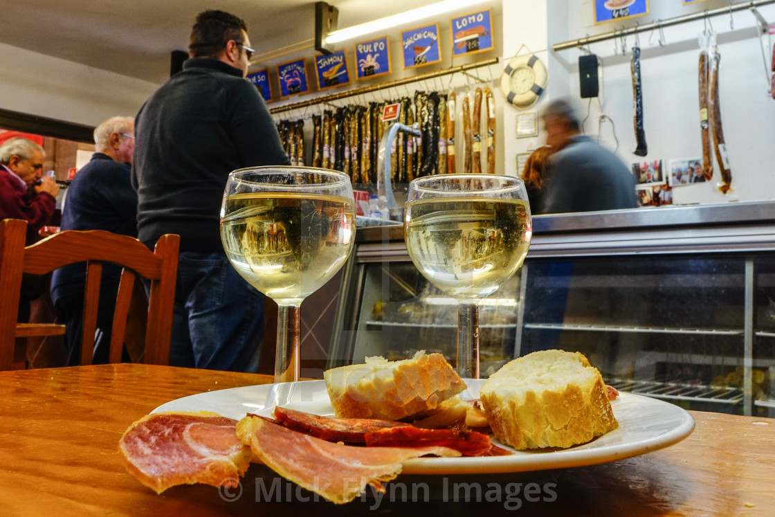 "Two glasses of white wine, bread, ham and chorizo tapas on a bar" stock image