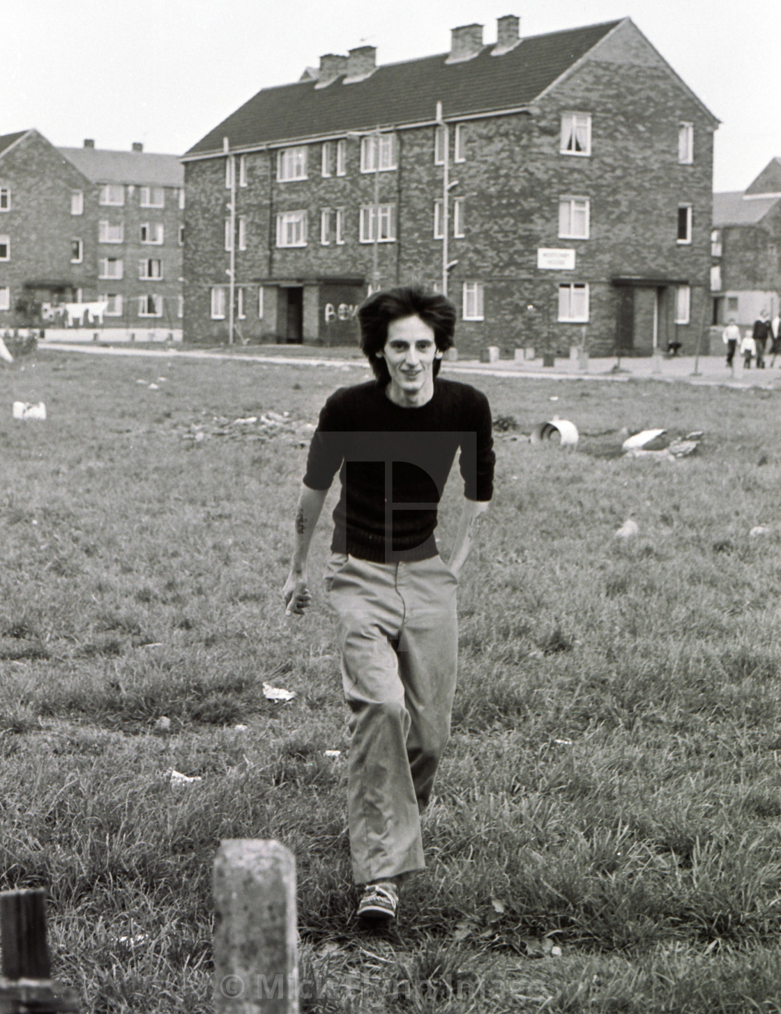 "Man crossing rubbish strewn field on a 1980's council estate" stock image