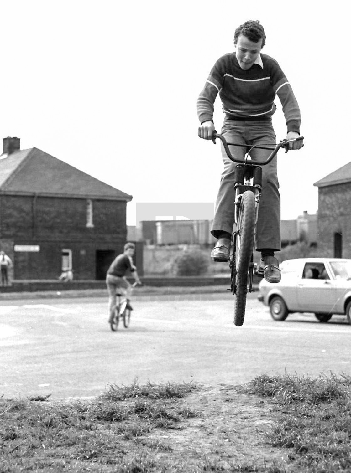 "Boys jumping on BMX type bikes on Council housing estate north of England 1982" stock image