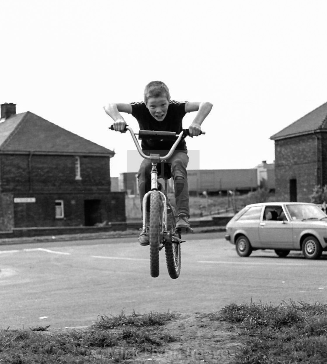 "Boys jumping on BMX type bikes on Council housing estate north of England 1982" stock image