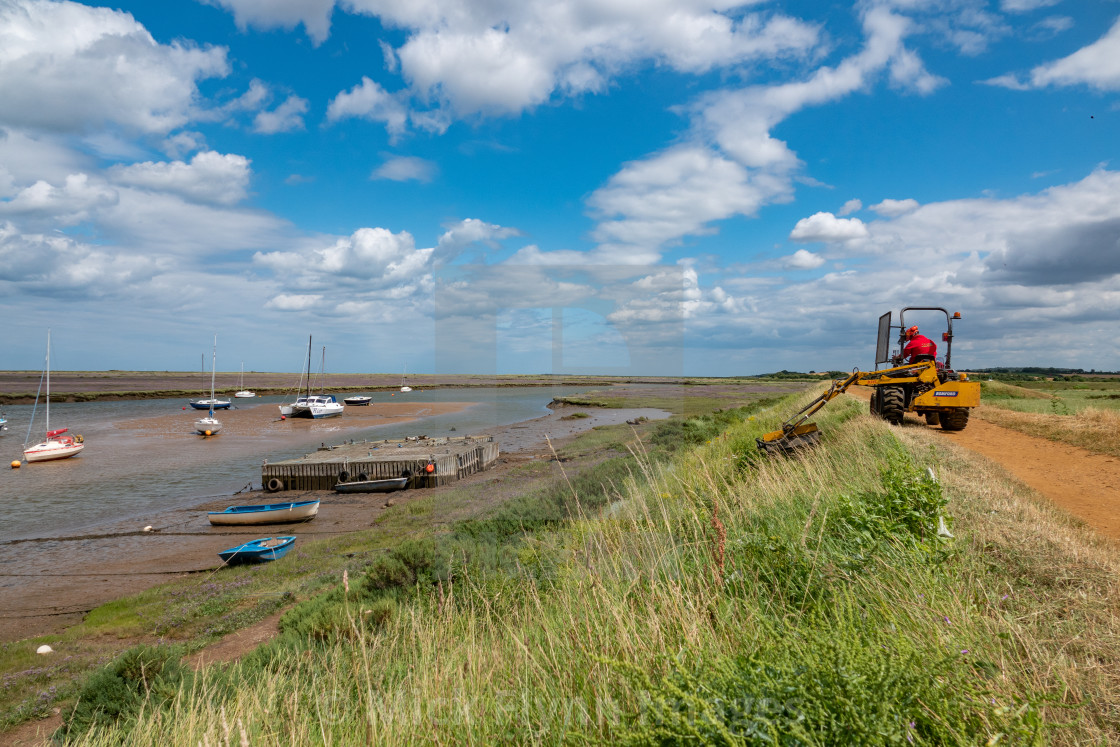 "Man using a ride on machine to cut grass beside a coastal footpath in..." stock image