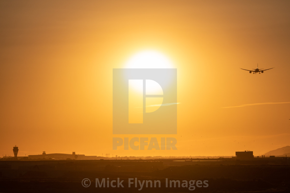 "Twin engined jet landing in Barcelona Airport at sunset, grainy shot with birds." stock image