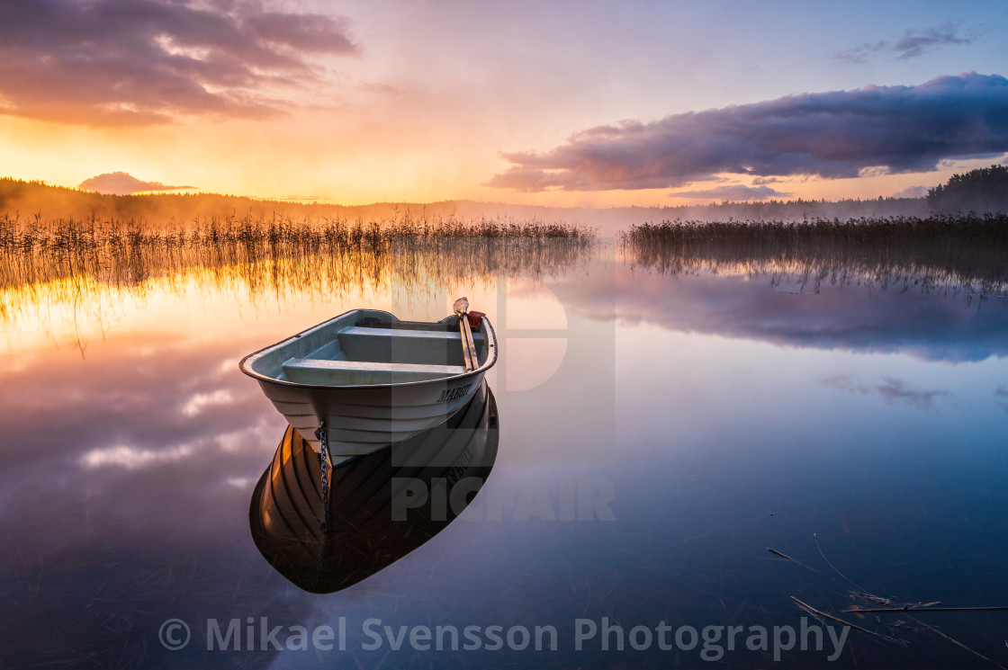 "Boat on still lake at sunrise, Sweden." stock image