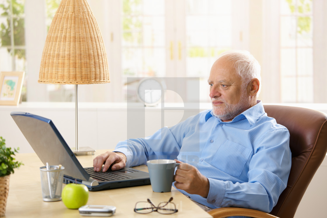 "Elderly man using computer, having coffee" stock image