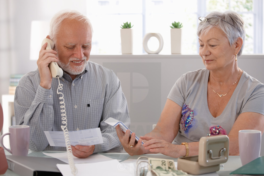 "Elderly couple checking bills at home" stock image