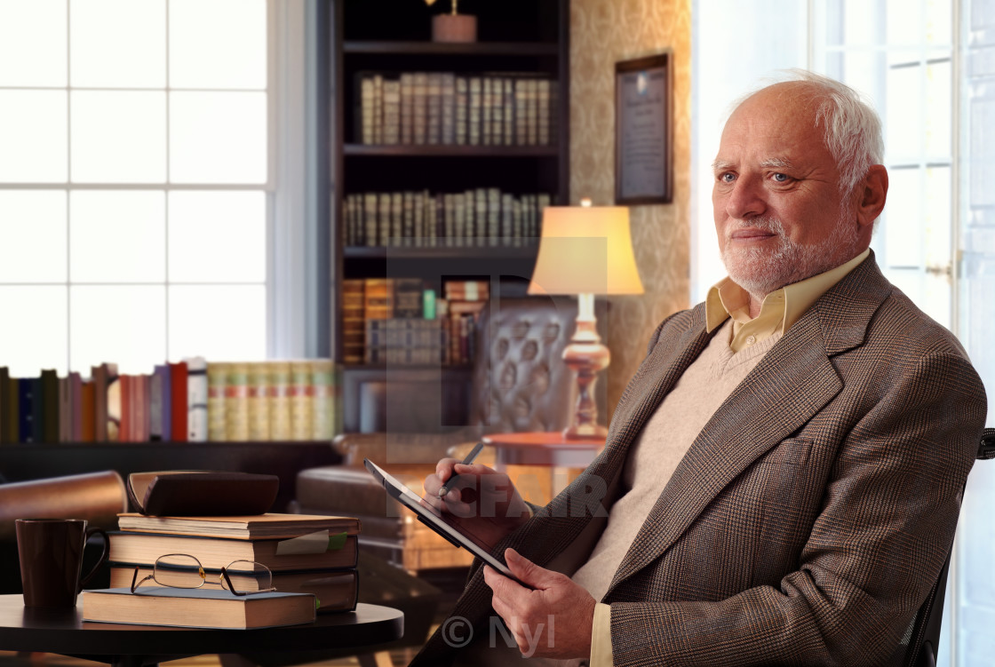 "Senior man at home library with books and tablet" stock image