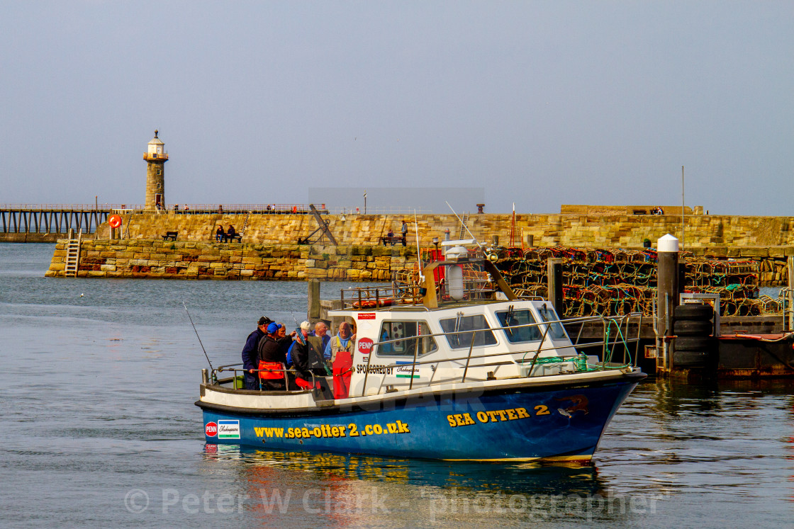"Sea Otter 2 Returning to Whitby Harbour on Yorkshires East Coast after a Fishing Trip. Pier and Lighthouse in the Background." by Peter W. Clark - 'photographer' - £10.00 "Sea Otter 2 Returning to Whitby Harbour on Yorkshires East Coast after a Fishing Trip. Pier and Lighthouse in the Background." stock image