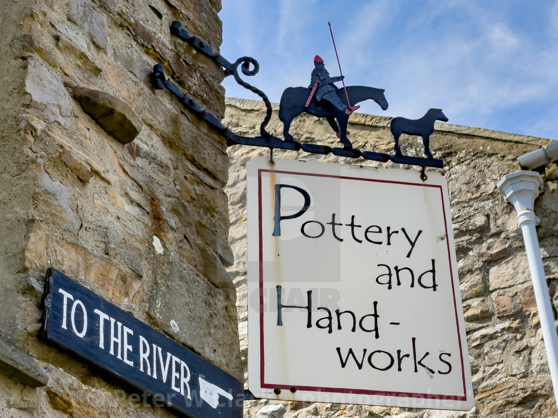 "Pottery and Handworks corner shop sign, Reeth, Swaledale. Also To The River direction sign." by Peter W. Clark - 'photographer' - £10.00 "Pottery and Handworks corner shop sign, Reeth, Swaledale. Also To The River direction sign." stock image