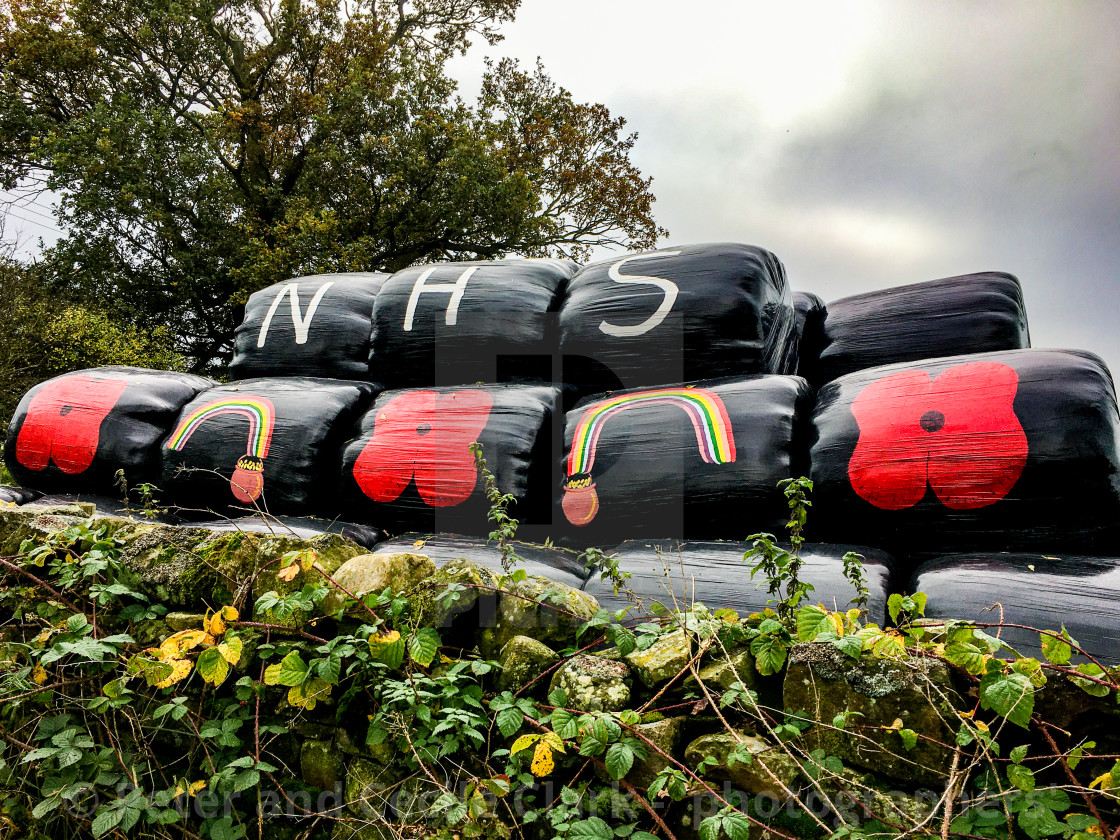 "Poppy Motif and NHS Logo with painted Rainbow and Pot of Gold on Plastic Covered Hay Bales." stock image