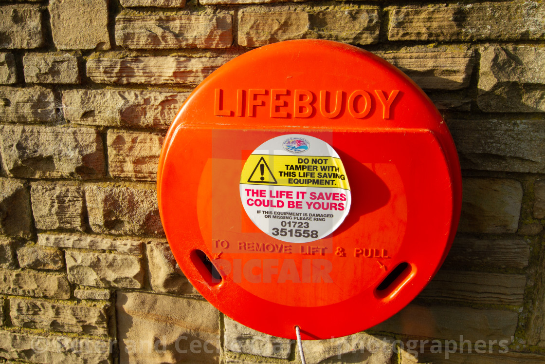 "Robin Hoods Bay, Lifebuoy on Sea Wall Walk, stone background." stock image