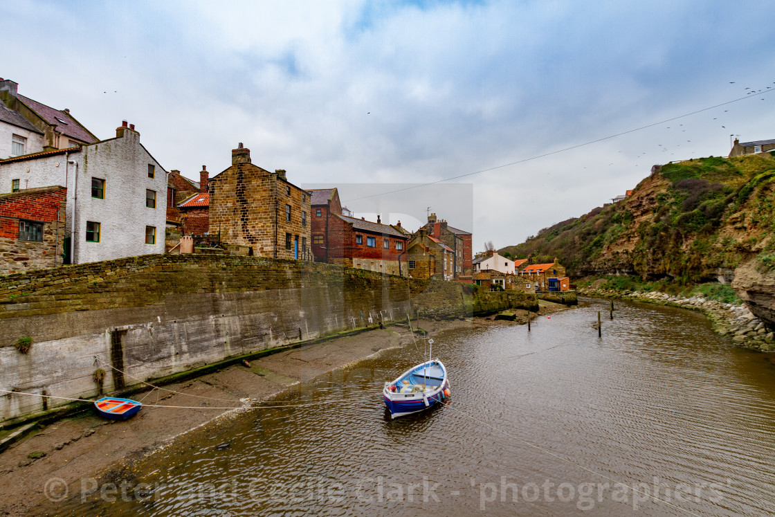 "Blue Fishing Cobble Moored in Staithes Beck, Retaining Wall and Cottages in the background." stock image