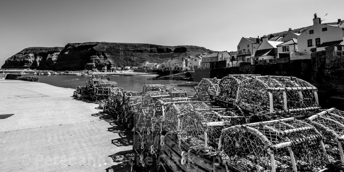 "Lobster Pots Stacked on North Side of Staithes Harbour, Yorkshire, England. (monochrome)" stock image