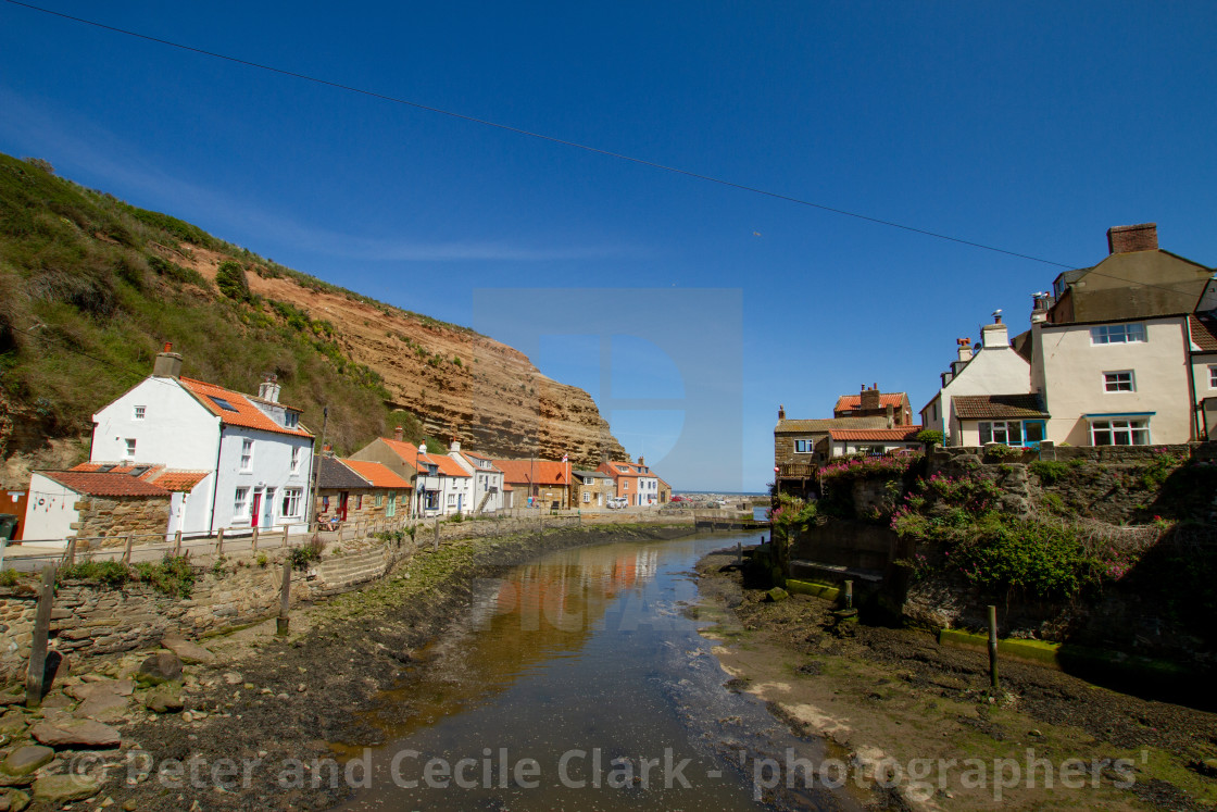 "View along Staithes Beck towards North Side Cottages, Cowbar Nab and the Harbour. Yorkshire, England." stock image