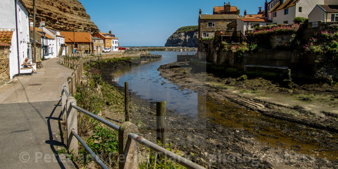 "View along Staithes Beck towards North Side Cottages, Cowbar Nab and the Harbour. Yorkshire, England." stock image