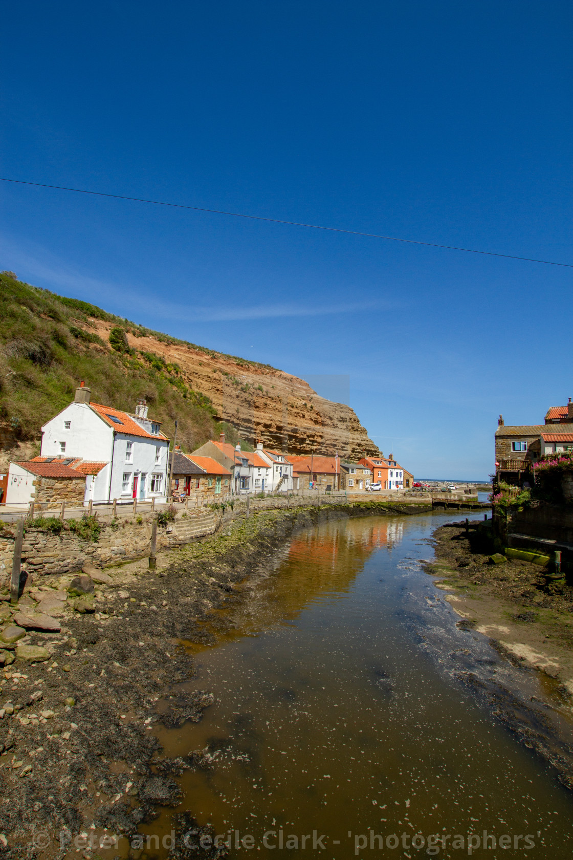 "View along Staithes Beck towards North Side Cottages, Cowbar Nab and the Harbour. Yorkshire, England." stock image