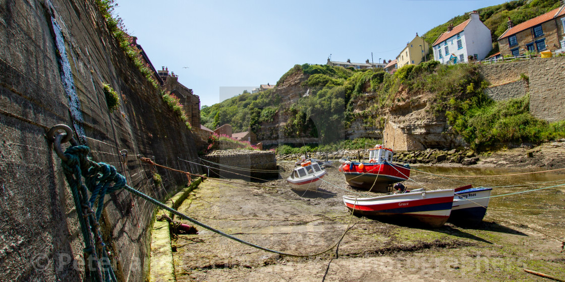 "Fishing Cobbles Moored in Staithes Beck, Fishermens Cottages in the Background. Staithes, Yorkshire, UK." stock image