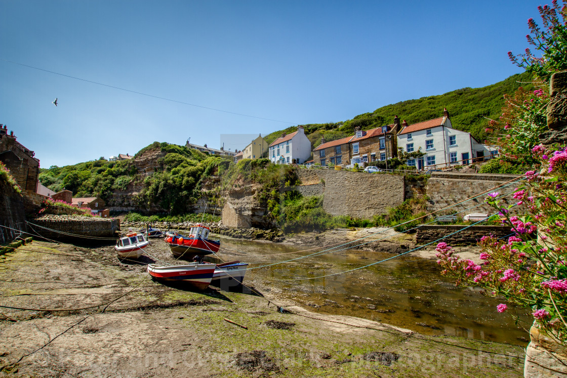 "Fishing Cobbles Moored in Staithes Beck, Fishermens Cottages in the Background. Staithes, Yorkshire, UK." stock image