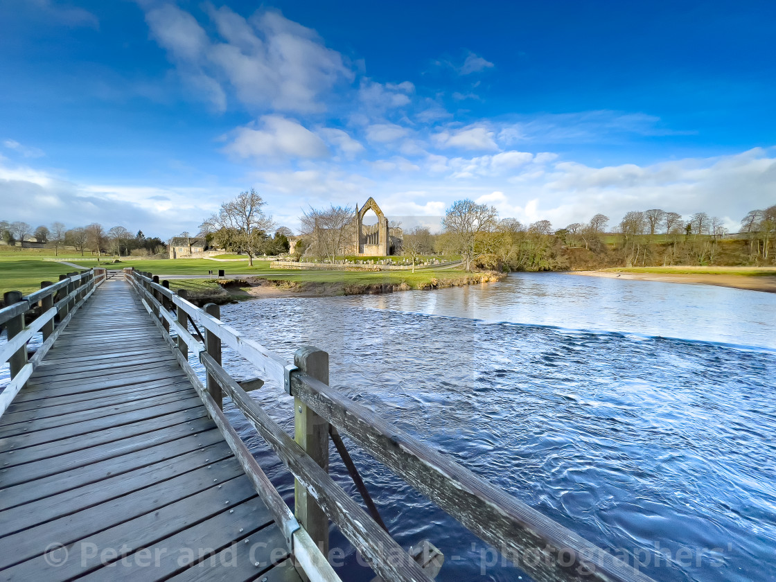 "River Wharfe Footbridge and Stepping Stones, Bolton Abbey, Priory Ruins in the Background." stock image