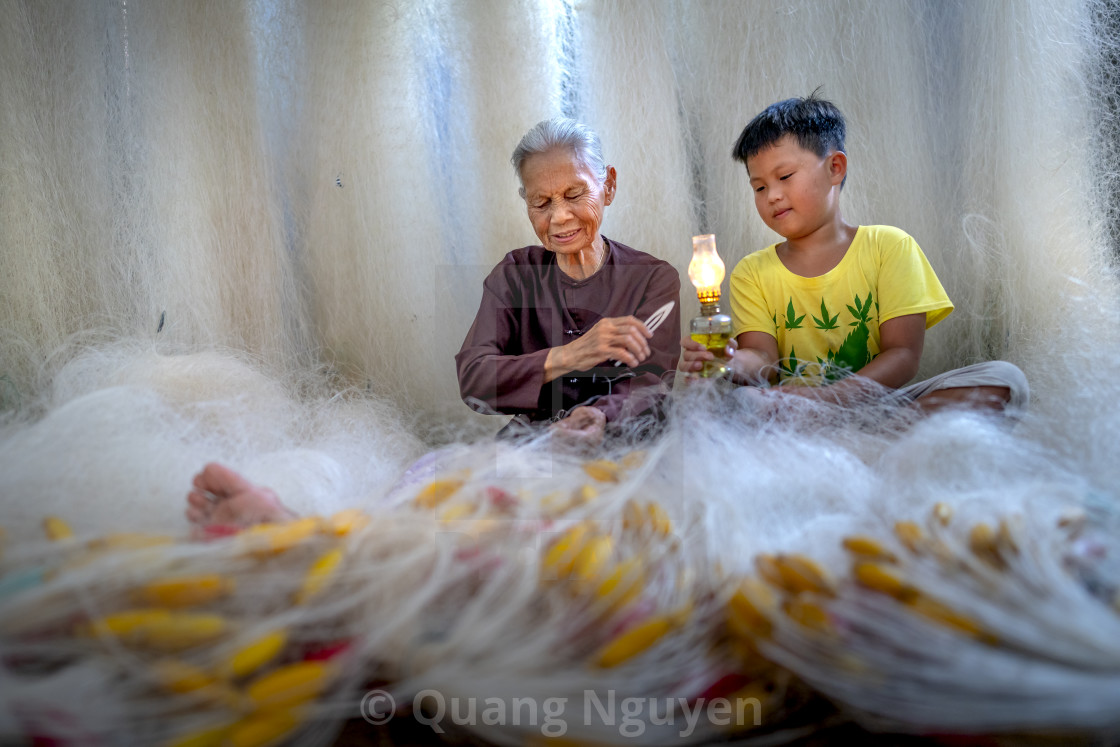 "two grandchildren sitting making a fishing net together" by Quang Nguyen - $43.35 "two grandchildren sitting making a fishing net together" stock image